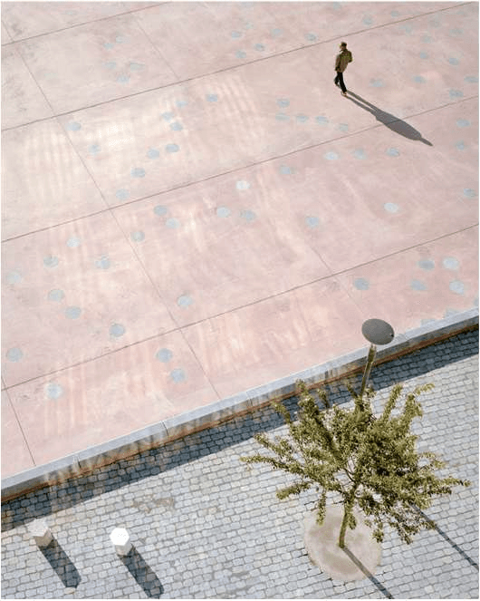 Aerial view of a paved square with a single figure crossing it